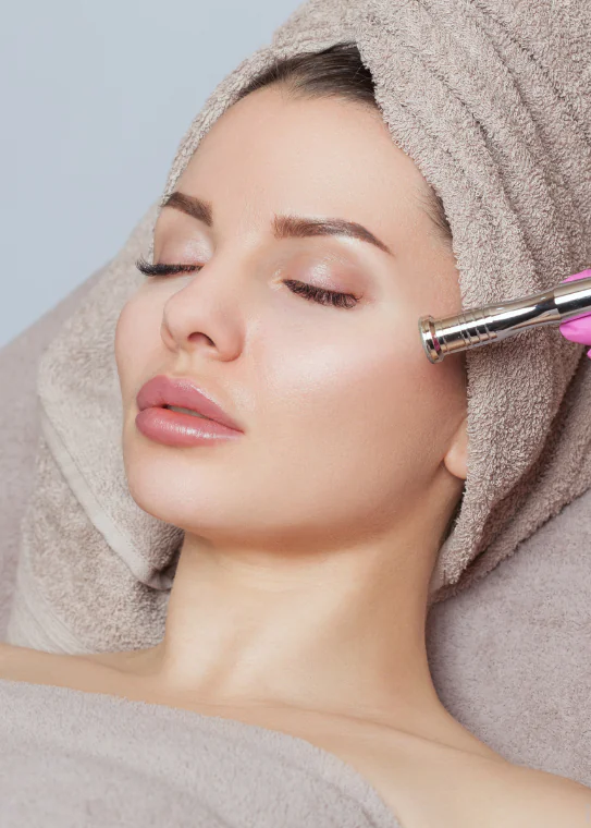 Client receiving a microdermabrasion facial treatment with a handheld wand